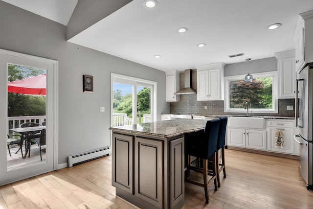 233 Church St, Hebron, CT 06231 - kitchen with baseboard heating, wall chimney exhaust hood, stainless steel built in refrigerator, a kitchen island, and light wood finished floors