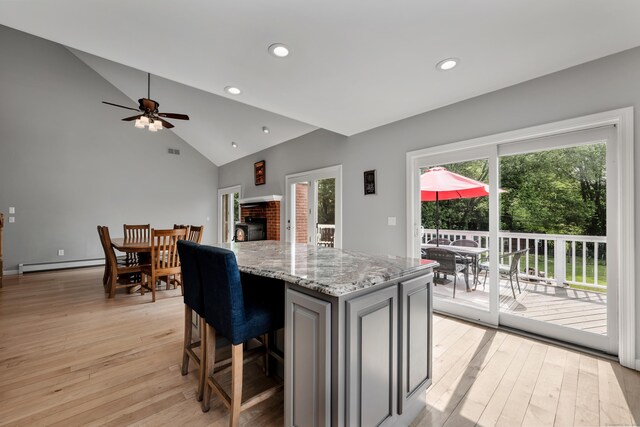 233 Church St, Hebron, CT 06231 - kitchen with lofted ceiling, light wood-type flooring, a kitchen island, baseboard heating, and light stone counters