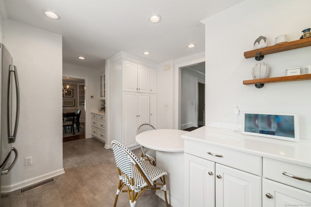 407 Meadowbrook Rd, Fairfield, CT 06824 - kitchen with freestanding refrigerator, white cabinets, recessed lighting, a breakfast bar area, and light countertops