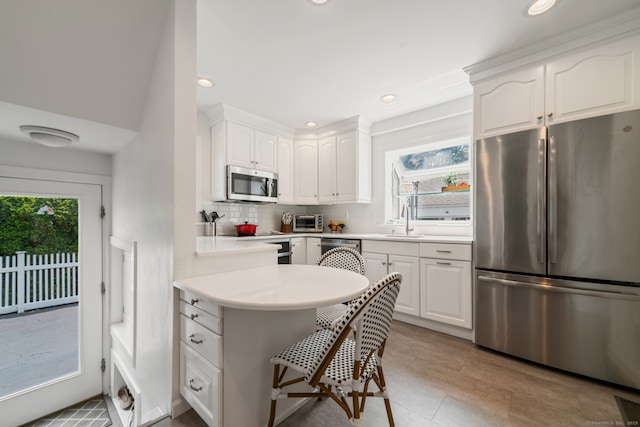 407 Meadowbrook Rd, Fairfield, CT 06824 - kitchen featuring stainless steel appliances, tasteful backsplash, white cabinets, a breakfast bar, and a sink