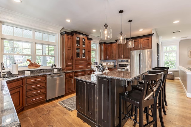 112 John Hand Dr, Coventry, CT 06238 - kitchen with stainless steel appliances, light wood-style floors, ornamental molding, dark stone counters, and a breakfast bar