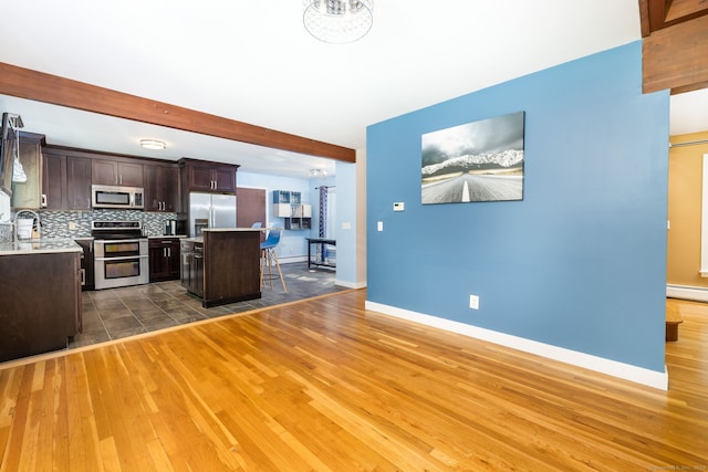 20 Roundhill Rd, Granby, CT 06035 - kitchen with stainless steel appliances, dark brown cabinetry, a center island, a breakfast bar, and light countertops