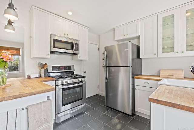 407 Sylvan Knoll Rd, Stamford, CT 06902 - kitchen featuring stainless steel appliances, wooden counters, white cabinetry, dark tile patterned floors, and glass insert cabinets