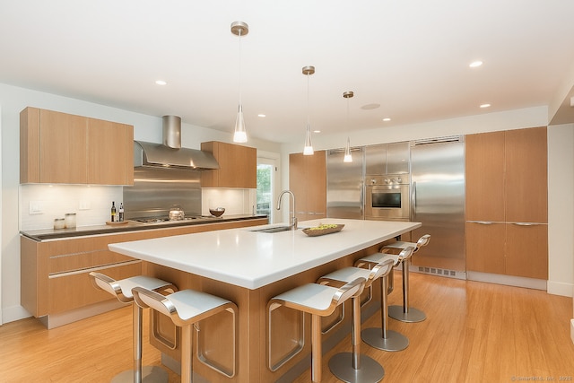 4 Berkeley Hl, Westport, CT 06880 - kitchen featuring stainless steel appliances, wall chimney exhaust hood, modern cabinets, light wood finished floors, and recessed lighting