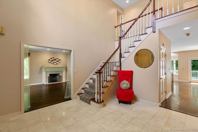 1 Mountaincrest Dr, Cheshire, CT 06410 - staircase with a high ceiling, a fireplace with raised hearth, baseboards, and tile patterned flooring