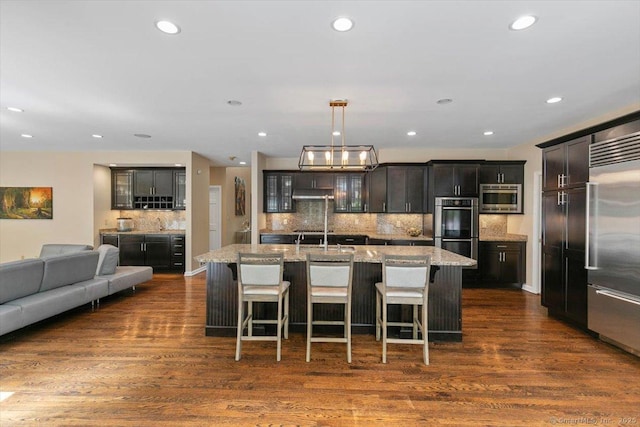 1 Mountaincrest Dr, Cheshire, CT 06410 - kitchen with built in appliances, glass insert cabinets, dark wood-style flooring, tasteful backsplash, and a breakfast bar