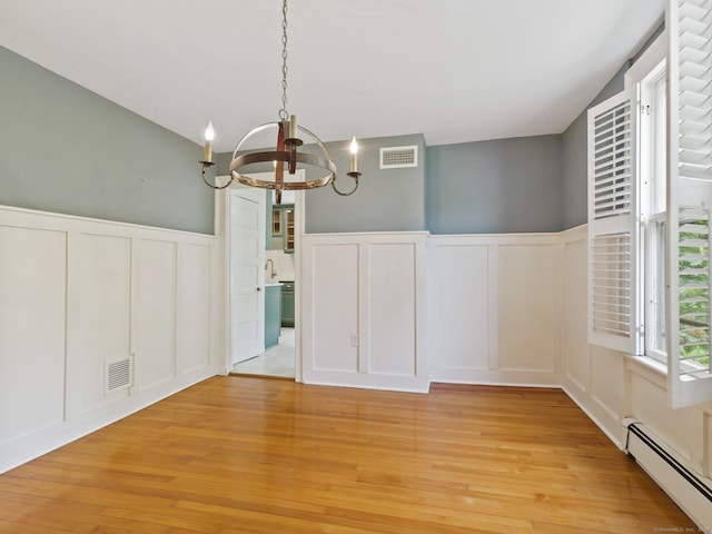 355 Main St, Old Saybrook, CT 06475 - unfurnished dining area featuring a decorative wall, a baseboard radiator, a chandelier, a wainscoted wall, and light wood-style flooring