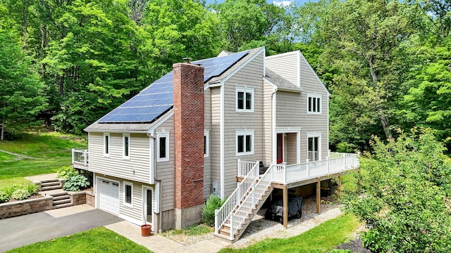 2 Pent Rd, Bloomfield, CT 06002 - view of front of house with stairway, driveway, a chimney, roof mounted solar panels, and a wooden deck