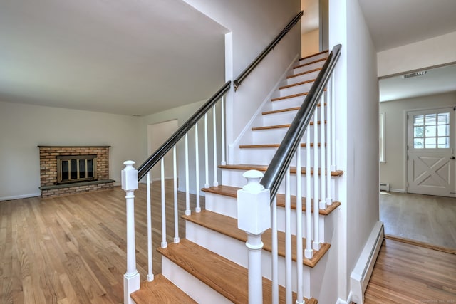 64 Regina St, Trumbull, CT 06611 - stairway featuring a baseboard heating unit, wood finished floors, a brick fireplace, and baseboards