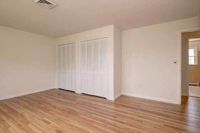 64 Regina St, Trumbull, CT 06611 - unfurnished bedroom featuring two closets, a baseboard heating unit, light wood-style flooring, and baseboards