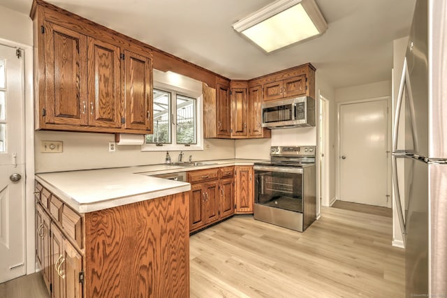 64 Regina St, Trumbull, CT 06611 - kitchen featuring appliances with stainless steel finishes, brown cabinets, light wood finished floors, and a sink