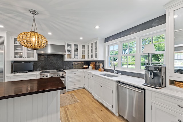 6 Over Rock Ln, Westport, CT 06880 - kitchen featuring appliances with stainless steel finishes, wall chimney range hood, a sink, butcher block counters, and healthy amount of natural light
