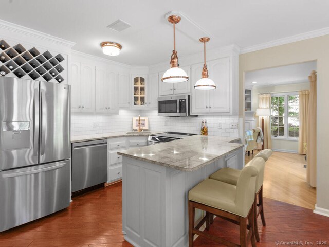 152 Hollyberry Rd, Bristol, CT 06010 - kitchen featuring appliances with stainless steel finishes, a peninsula, white cabinetry, a breakfast bar area, and ornamental molding