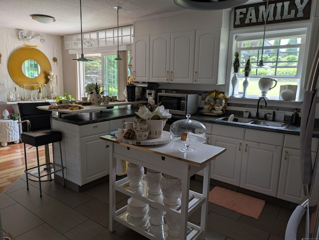 101 Chipper Rd, Waterbury, CT 06704 - kitchen with stainless steel microwave, a sink, dark countertops, white cabinetry, and plenty of natural light