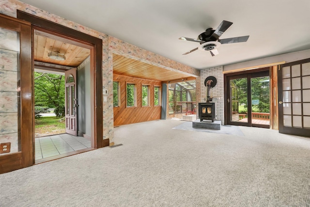 283 Derby Ave, Orange, CT 06477 - unfurnished living room with a wood stove, a ceiling fan, carpet, and wood walls