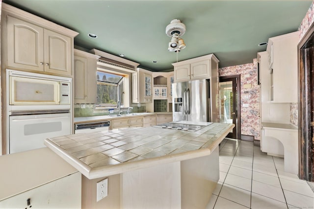 283 Derby Ave, Orange, CT 06477 - kitchen with white appliances, tile countertops, light tile patterned flooring, wallpapered walls, and a kitchen island