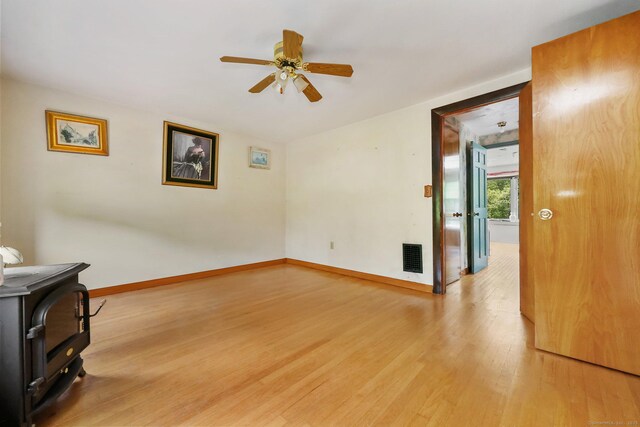 283 Derby Ave, Orange, CT 06477 - unfurnished living room featuring light wood-style floors, a wood stove, and a ceiling fan