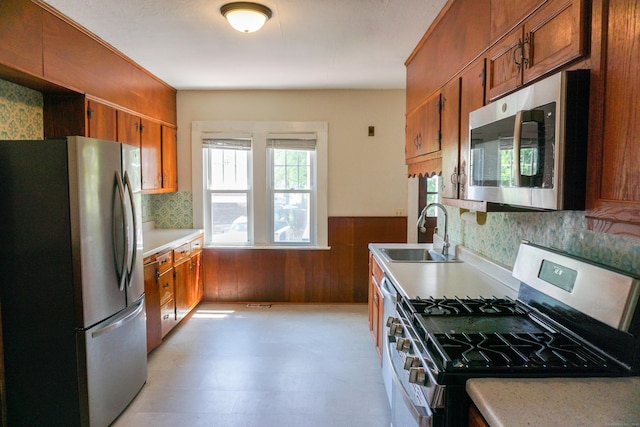 47 Mountford St, Hartford, CT 06114 - kitchen with stainless steel appliances, brown cabinetry, light countertops, wainscoting, and wood walls