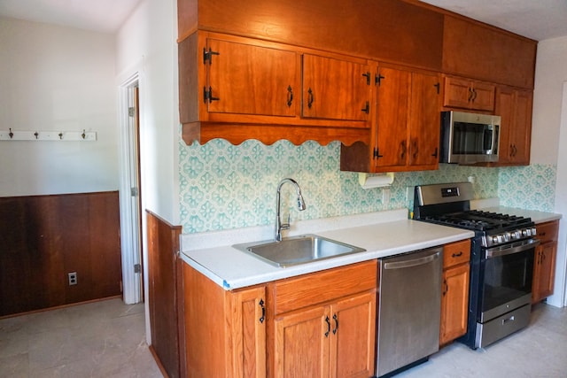 47 Mountford St, Hartford, CT 06114 - kitchen featuring appliances with stainless steel finishes, brown cabinetry, light countertops, decorative backsplash, and a wainscoted wall