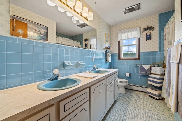 2 Marion Ln, Canterbury, CT 06331 - bathroom featuring a baseboard radiator, tile walls, double vanity, toilet, and wallpapered walls