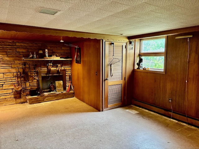 56 Clapboard Ridge Rd, Danbury, CT 06811 - unfurnished living room with tile patterned floors, a baseboard radiator, wood walls, and a stone fireplace