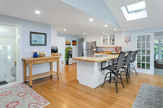 19 Orchard Ln, New Canaan, CT 06840 - kitchen with freestanding refrigerator, a breakfast bar, white cabinetry, butcher block counters, and light wood-style floors