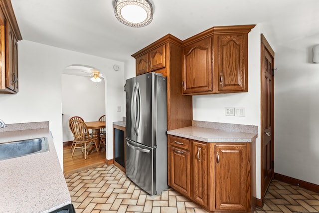 72 Westminster St, Hamden, CT 06518 - kitchen featuring freestanding refrigerator, a sink, arched walkways, light countertops, and brown cabinetry