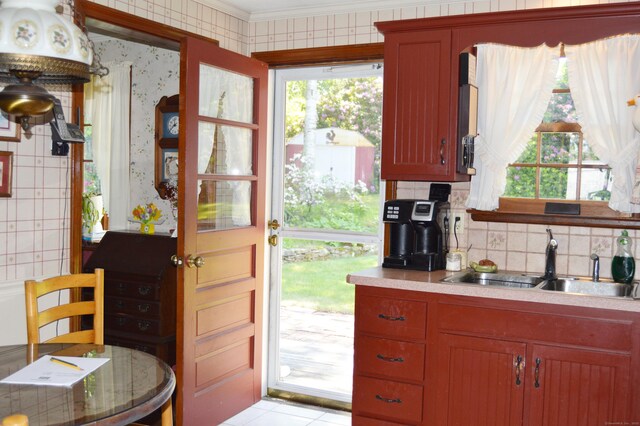 76 Country Ln, Bristol, CT 06010 - kitchen with wallpapered walls, a sink, ornamental molding, decorative backsplash, and light countertops