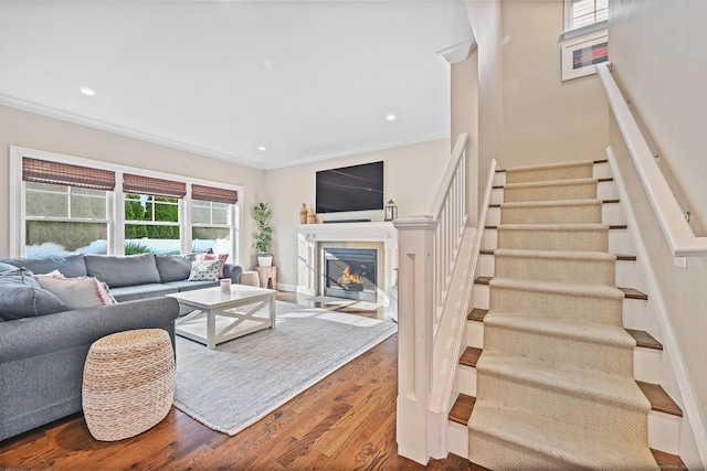living room with stairway, ornamental molding, wood finished floors, a tile fireplace, and recessed lighting
