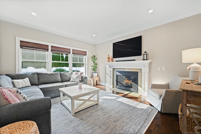 living area with wood finished floors, ornamental molding, a tiled fireplace, and recessed lighting