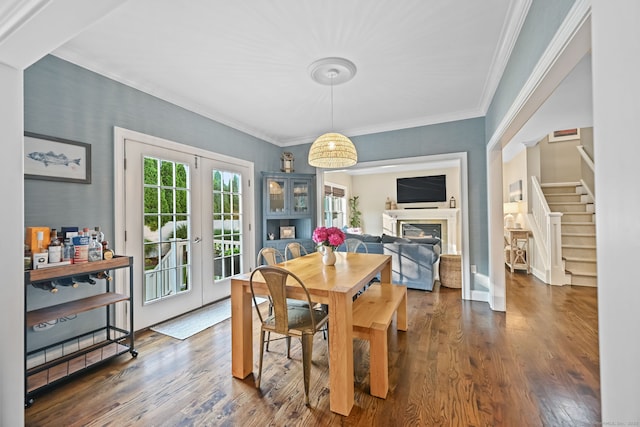 dining space with french doors, stairs, dark wood-style floors, crown molding, and a glass covered fireplace