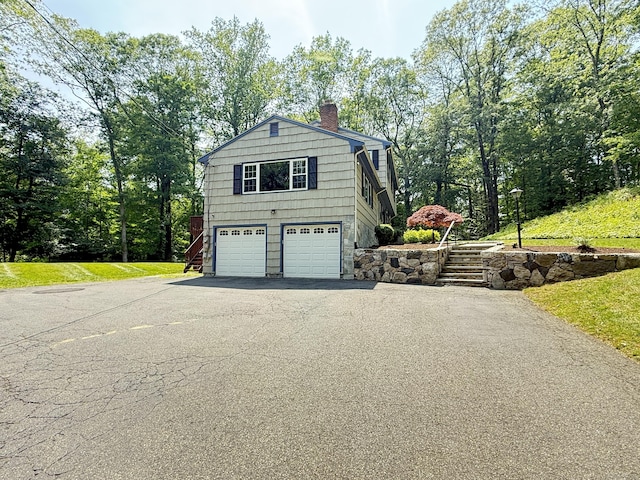 51 Boulder Brook Dr, Stamford, CT 06903 - view of home's exterior featuring driveway, a chimney, an attached garage, and stairway