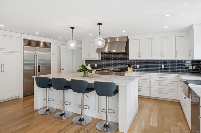 27 Waverly Rd, Darien, CT 06820 - kitchen featuring wall chimney range hood, appliances with stainless steel finishes, white cabinets, decorative backsplash, and light wood-style floors