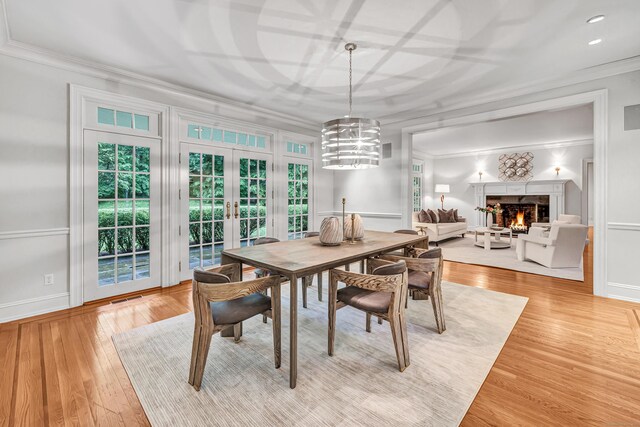 4 Lyons Plain Rd, Weston, CT 06883 - dining space featuring crown molding, a lit fireplace, light wood finished floors, french doors, and a chandelier