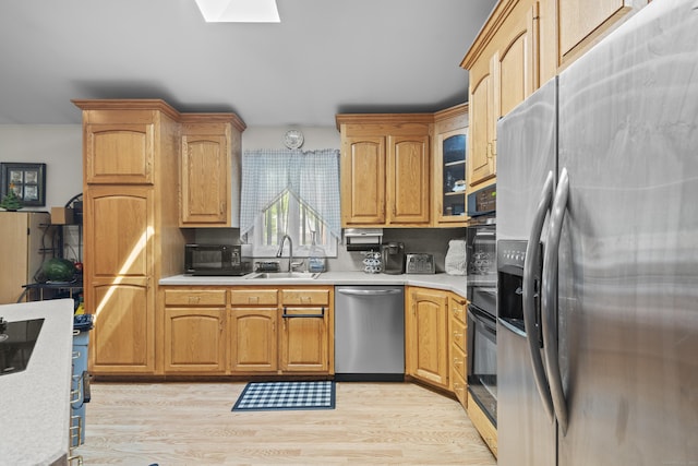 337 Woodbine Rd, Stamford, CT 06903 - kitchen featuring stainless steel appliances, a sink, light countertops, light wood-style flooring, and a skylight
