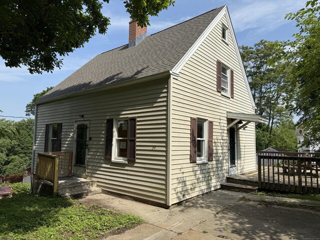 34 Buckingham Ave, Norwich, CT 06360 - view of front of home featuring a chimney, a deck, a patio area, and roof with shingles