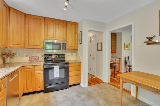 19 Oak Leaf Cir, Coventry, CT 06238 - kitchen with stainless steel microwave, black range with electric stovetop, decorative backsplash, and light stone counters