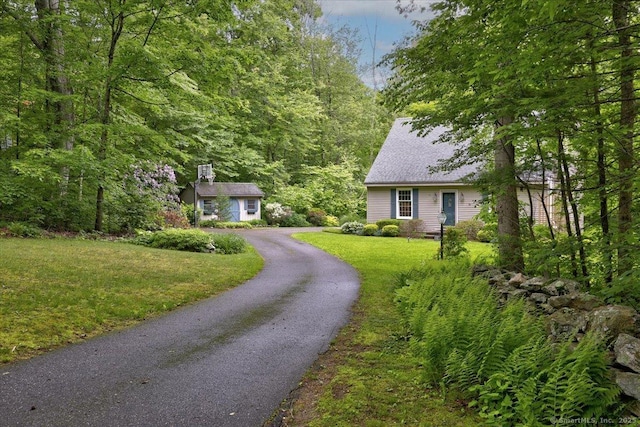 19 Oak Leaf Cir, Coventry, CT 06238 - view of front facade with a front lawn, a forest view, a shingled roof, and asphalt driveway