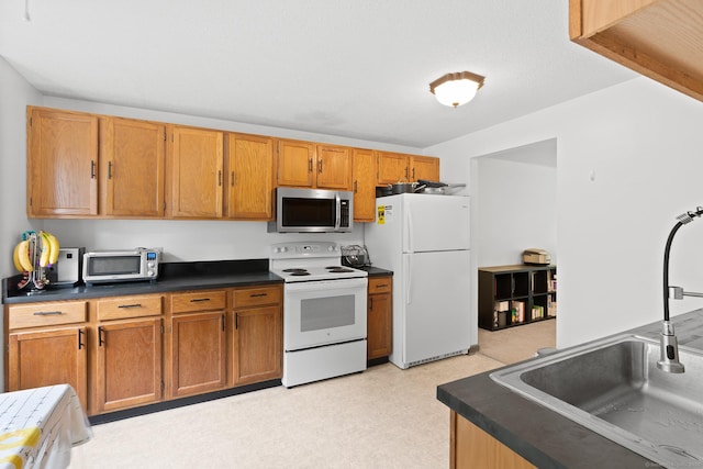 122 W Main St Apt E, Stafford, CT 06076 - kitchen with white appliances, a sink, dark countertops, brown cabinets, and light flooring