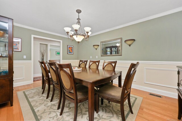 15 Oakledge Cir, Norwalk, CT 06854 - dining area featuring light wood-type flooring, a chandelier, ornamental molding, and a wainscoted wall