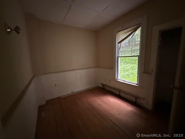 29 Division St, Norwich, CT 06360 - unfurnished room with wood finished floors and a baseboard heating unit
