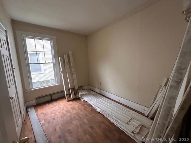 29 Division St, Norwich, CT 06360 - unfurnished room with wood finished floors, ornamental molding, and a baseboard radiator