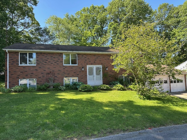 back of house featuring a lawn, brick siding, a garage, and driveway