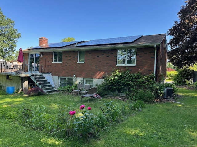 rear view of house with stairs, a chimney, a lawn, and brick siding