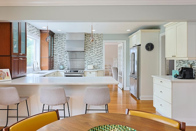 402 Jones Hill Rd, West Haven, CT 06516 - kitchen featuring stainless steel appliances, decorative backsplash, custom exhaust hood, a peninsula, and a kitchen bar
