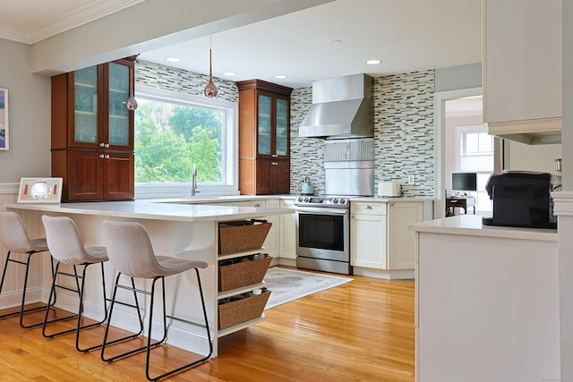 402 Jones Hill Rd, West Haven, CT 06516 - kitchen with wall chimney range hood, stainless steel electric range, crown molding, a kitchen bar, and light countertops