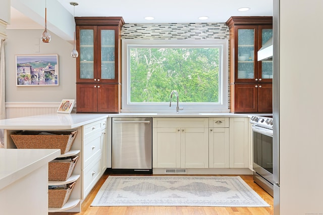 402 Jones Hill Rd, West Haven, CT 06516 - kitchen featuring appliances with stainless steel finishes, light countertops, light wood-type flooring, pendant lighting, and glass insert cabinets