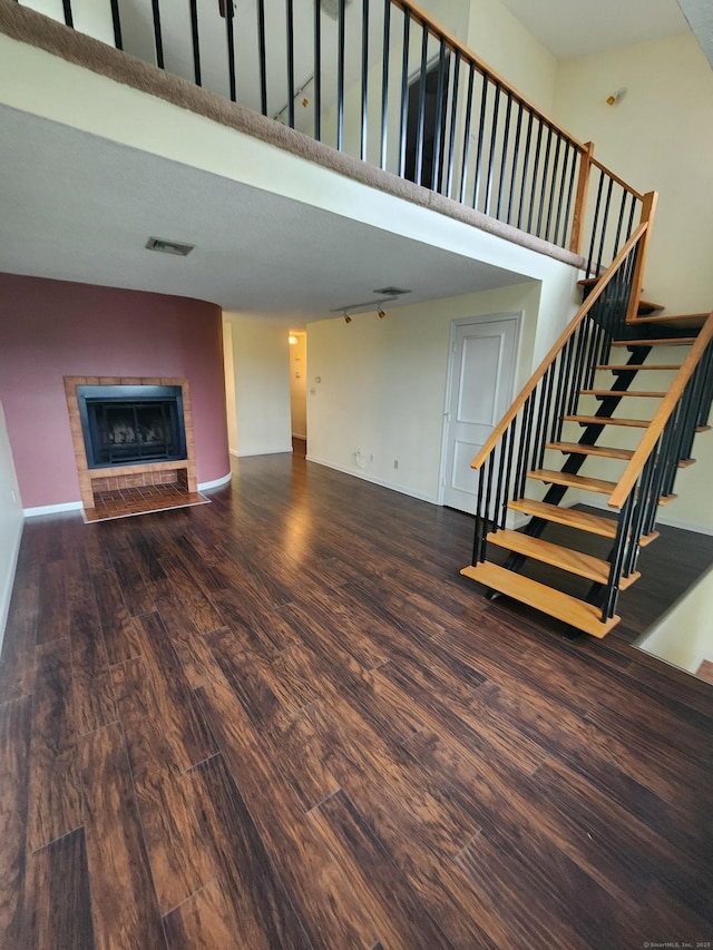 280 Brittany Farms Rd Apt C, New Britain, CT 06053 - unfurnished living room featuring wood finished floors, a towering ceiling, a fireplace with flush hearth, and stairway