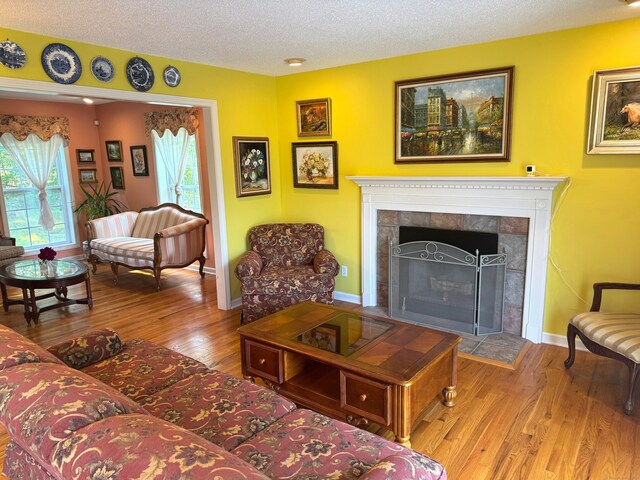 29 Swift St, Branford, CT 06405 - living room with wood finished floors, a tile fireplace, a textured ceiling, and baseboards
