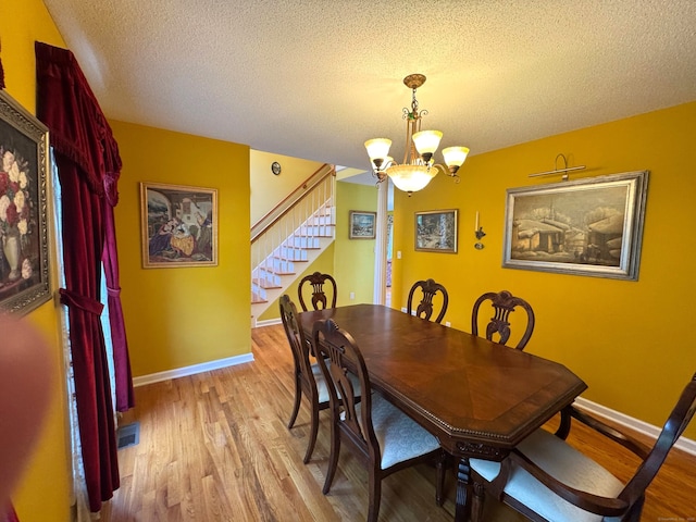 29 Swift St, Branford, CT 06405 - dining space featuring stairs, a chandelier, a textured ceiling, wood finished floors, and baseboards